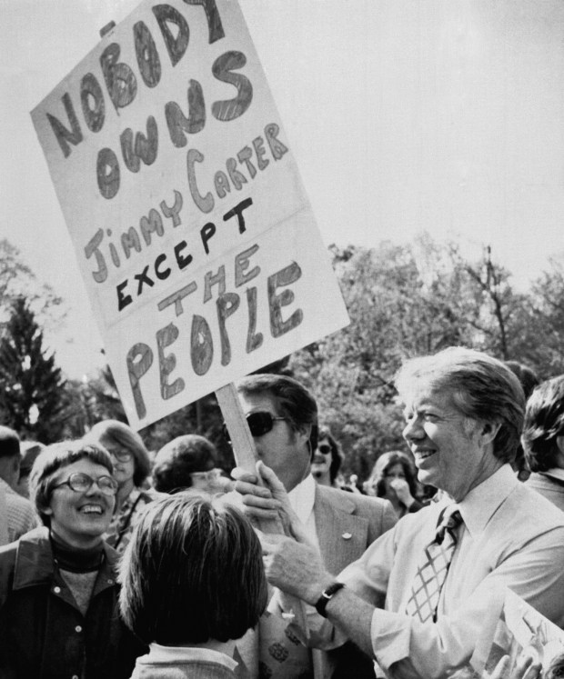 Democratic presidential hopeful, former Georgia Gov. Jimmy Carter, holds a poster as he mingles with the crowd during a campaign visit