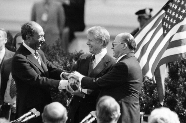 Egyptian President Anwar Sadat, President Jimmy Carter and Israeli Prime Minister Menachem Begin clasp hands to symbolize their agreement after signing the Middle East Peace Treaty at the White House