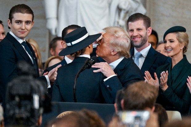 President Donald Trump, center right, reaches to kiss wife Melania Trump as his children Barron Trump, from left, Eric Trump and Ivanka Trump watch during the 60th Presidential Inauguration in the Rotunda of the U.S. Capitol in Washington, Monday, Jan. 20, 2025. (Kenny Holston/The New York Times via AP, Pool)