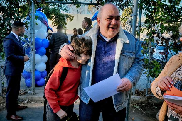 Palisades Charter Elementary School 3rd grade student Jaden Koshki cries in his father's arm Joseph Koshki upon arriving at his new school