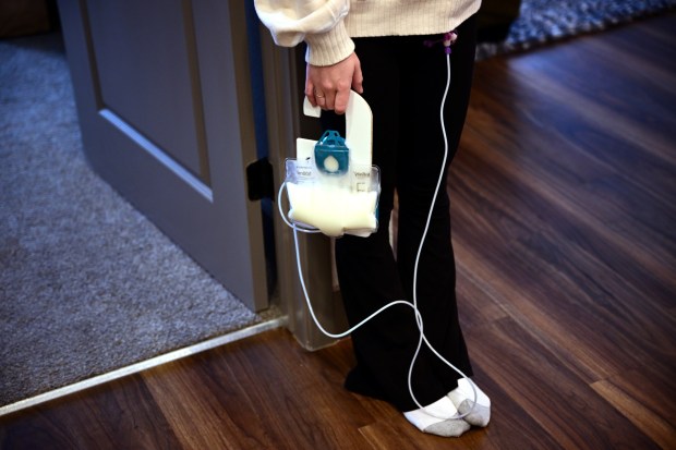 Lilly Downs, 20, holds a feed pump bag of formula she uses for calorie intake while at her apartment in Fort Collins, Colorado on Thursday, Oct. 17, 2024. Four years after becoming sick with COVID-19, Downs is now a social media influencer spreading awareness about chronic illnesses. (Photo by Hyoung Chang/The Denver Post)