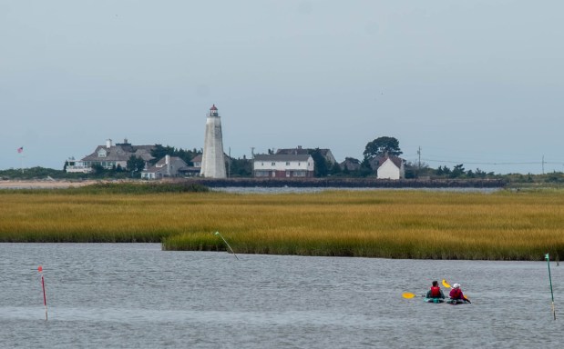 A pair of kayakers paddle down the Black Hall River in Old Lyme with the Lynde Point Lighthouse in Old Saybrook in the background on Friday, Sept. 6, 2024. (Aaron Flaum/Hartford Courant)