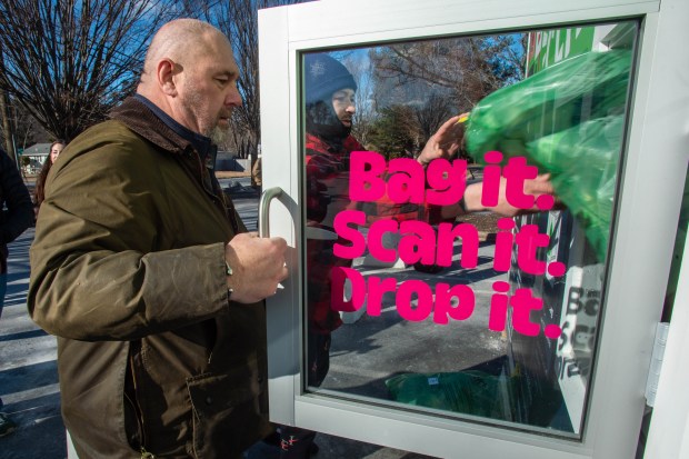 Dan Kiley from CLYNK holds the door as he helps David Gonzalez of Bristol, deposit his first bags of recyclables at a CLYNK redemption container at the Stop and Shop parking lot along Farmington Ave. in Bristol on Tuesday, Jan. 14, 2025. (Aaron Flaum/Hartford Courant)