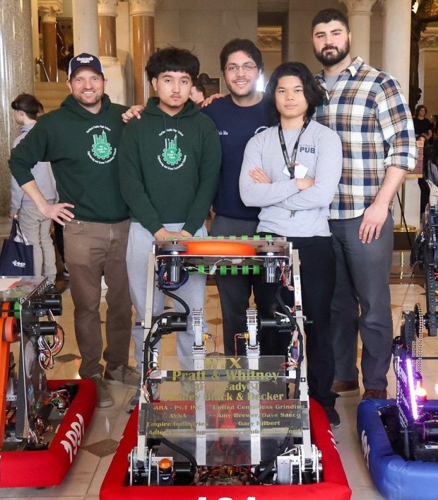 FIRST robotics participants from Hartford Public High School and the robot they built are flanked by their mentors following demonstration of their creation at a manufacturing career fair held at the Connecticut State Capitol, March 2024.