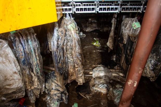 Flood damaged clothes hang on the rack in the basement of Village Fabric Care Center at the Klarides Village shopping center in Seymour after a huge flood on August 18, 2024. (Aaron Flaum/Hartford Courant)